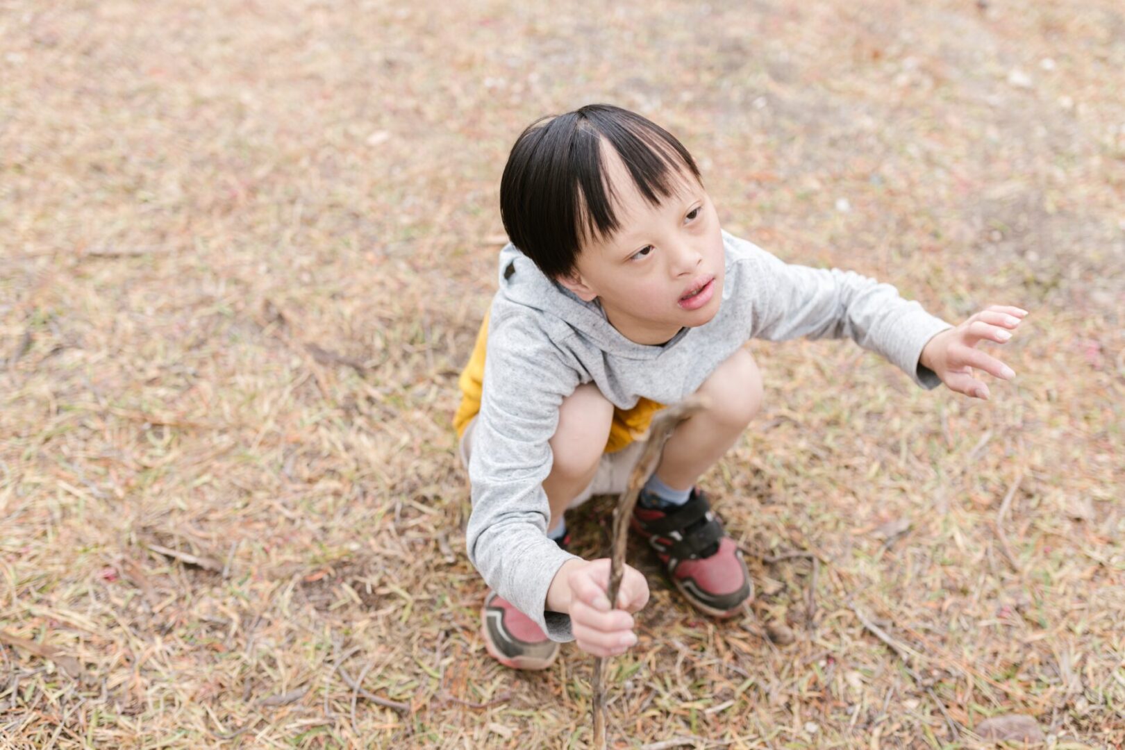 A young boy kneeling down in the dirt.